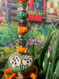 a stack of beads sitting on top of an orange object in front of some plants