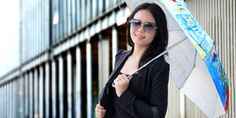 a woman holding an umbrella while standing in front of a building on a sunny day