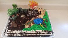 a birthday cake decorated with dirt, plants and animals is on a countertop next to a clock