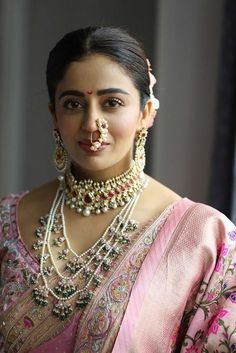 a woman in a pink sari with jewelry on her neck and nosepieces