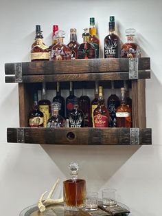 a wooden shelf filled with liquor bottles and glasses on top of a glass table next to an antler