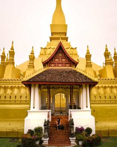 a person sitting on steps in front of a building with gold roof and spires