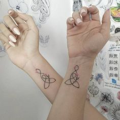 two people with matching tattoos on their arms holding each other's hands in the air