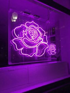 a lighted rose is in the window of a building at night, it appears to be purple