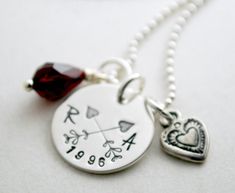 "Sterling silver, hand stamped necklace with custom initials and anniversary date. A 5/8\" sterling silver charm will be hand stamped with the initials of your choice in the font shown. The initials are on either side of the \"arrow hearts\". The year of your choice is stamped on the bottom edge of the charm. Hanging with the pendant is a small sterling silver heart charm, one tear drop shaped Swarovski crystal in the birth month color of your choice and a freshwater pearl. This necklace comes o Classic Personalized Charm Necklace For Anniversary, Personalized Classic Charm Necklace For Anniversary, Engraved Silver Charm Necklace For Anniversary, Engraved Silver Charm Necklace Anniversary Gift, Engraved Sterling Silver Charm Necklaces For Anniversary Gift, Sterling Silver Engraved Charm Necklaces For Anniversary Gift, Classic Sterling Silver Charm Necklace For Anniversary, Classic Hand Stamped Jewelry For Anniversary, Hand Stamped Charm Necklaces For Mother's Day Anniversary Gift