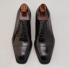 a pair of black leather shoes on a white surface