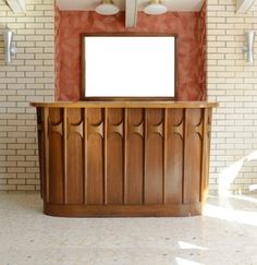 a wooden counter with a white screen mounted to it's side in front of a brick wall