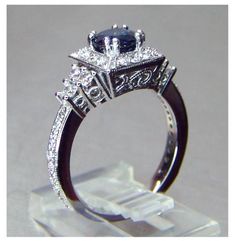 an engagement ring with diamonds and a blue stone in the center on a clear stand