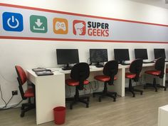 there are many computers on the desks in this computer room, all lined up with red chairs