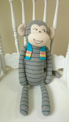 a sock monkey sitting on top of a white chair with a blue scarf around it's neck