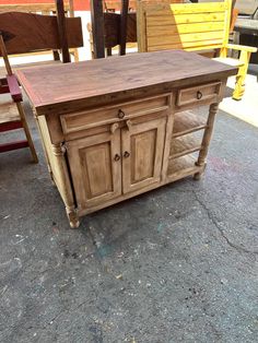 a wooden table sitting on top of a cement floor next to two chairs and a bench