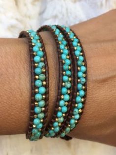 a woman's arm with two bracelets on top of each other, one has turquoise beads and the other has brown leather