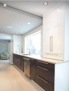 a large kitchen with white cabinets and wood flooring is pictured in this image, there are no people around the room