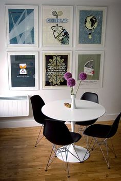 a white table with black chairs and pictures on the wall