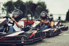 three people in go kart racing cars with helmets on