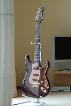 an electric guitar sitting on top of a table in front of a flat screen tv