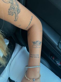 a woman with tattoos on her arm sitting in a car