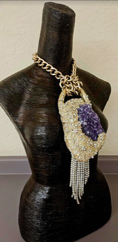 Here's a piece I had forgotten to list. A set a rough purple amethyst into a baroque style sculpture, painted it metallic gold and then heavily studded it with rhinestones. An angled silver tone rhinestone fringe sways from the bottom left hand corner which gives additional drama to the piece. The pendant measures 12" x 4" from the bail to the bottom of the rhinestone fringe. A warm gold large cable link chain suspends the piece and has an approximate 9" drop on each side. It closes with an xl f Luxury Purple Jeweled Jewelry, Luxury Handmade Purple Jewelry, Artisan Amethyst Jewelry With Stones, Gold Amethyst Jewelry With Stone Setting, Luxury Purple Jewelry For Collectors, Amethyst Gemstone Jewelry For Parties, Purple Crystal Jewelry With Stones, Luxury Purple Stone Jewelry, Luxury Purple Jewelry With Stones