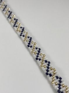 a white and blue beaded bracelet with gold clasps on a white table top