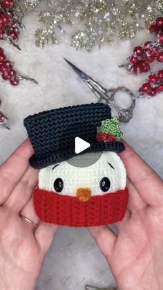 someone is holding a small knitted snowman ornament