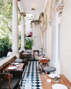 an outdoor dining area with black and white checkered flooring, wooden tables and chairs