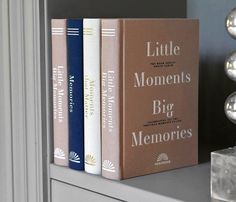 three books sitting on top of a book shelf next to a glass vase and lamp