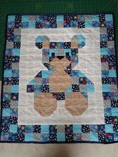 a quilted teddy bear sitting on top of a blue and white table cloth with stars