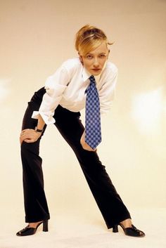 a woman in black pants and a white shirt with a blue tie