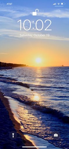 an iphone screen with the sun setting in the background and water on the beach below it