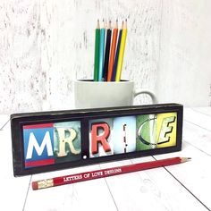 a pencil holder with the word mr and mrs spelled in different letters next to a cup full of pencils