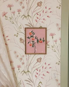 a bathroom with floral wallpaper and pink framed artwork