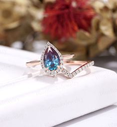 a blue and white diamond ring sitting on top of a napkin with flowers in the background