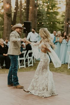 a bride and groom dancing at their wedding reception in the woods with guests watching them