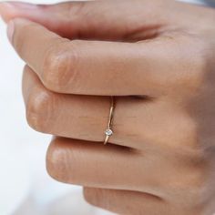 a woman's hand wearing a gold ring with a diamond on the middle finger