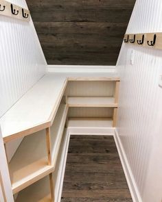 the inside of a white closet with wooden shelves