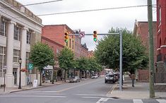 an empty street with cars parked on the side and traffic lights hanging over the road