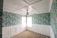 an empty room with floral wallpaper and white trim on the walls is seen in this image