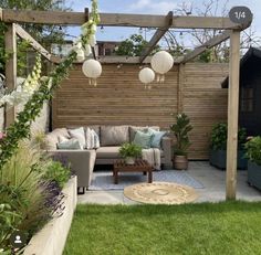 an outdoor living area with couches, tables and potted plants on the grass