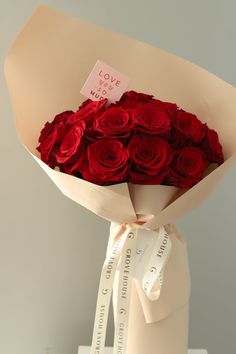 a bouquet of red roses in a vase with a ribbon tied around the end and a love note attached to it