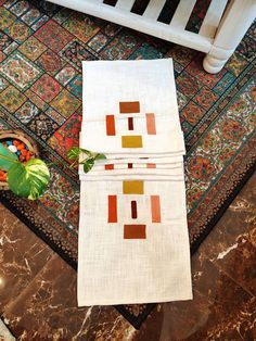 a white towel with an orange and yellow design on it sitting next to a potted plant