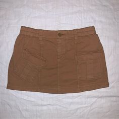 Khaki / Tan / Brown Cargo Skirt With Pockets Flattering And Comfortable Fit Excellent Condition- Never Worn! Brown Cotton Mini Skirt With Pockets, Brown Cargo Skirt With Pockets For Spring, High Waist Brown Skort With Pockets, Casual Brown Skort With Pockets, Casual Brown Relaxed Fit Skirt, Brown Mini Skort With Pockets, Casual Brown Relaxed Skirt, Fitted Brown Skort With Pockets, Relaxed Fit Brown Cotton Skirt