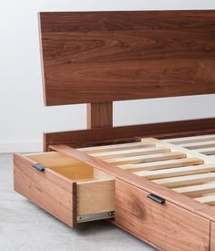 a wooden bed frame with drawers underneath it