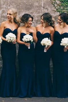 a group of women standing next to each other wearing dresses and holding bouquets in their hands