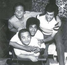 an old black and white photo of four men posing for the camera with their arms around each other