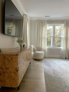 a living room filled with furniture and a flat screen tv mounted on the wall next to a window