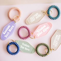 six different colored hair ties on top of a pink surface with the words custom tied here