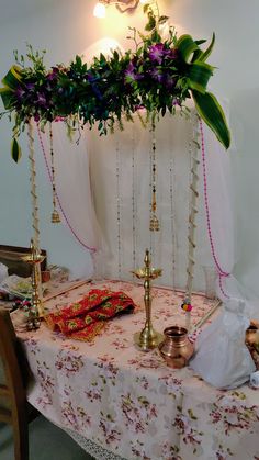 a table with flowers and candles on it in front of a wall hanging from the ceiling