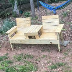 a wooden bench sitting in the middle of a yard next to a hammock