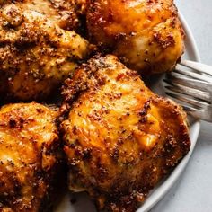 a white plate topped with chicken wings next to a fork on a gray counter top