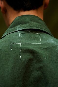 the back of a man's green shirt with white lines drawn on it,